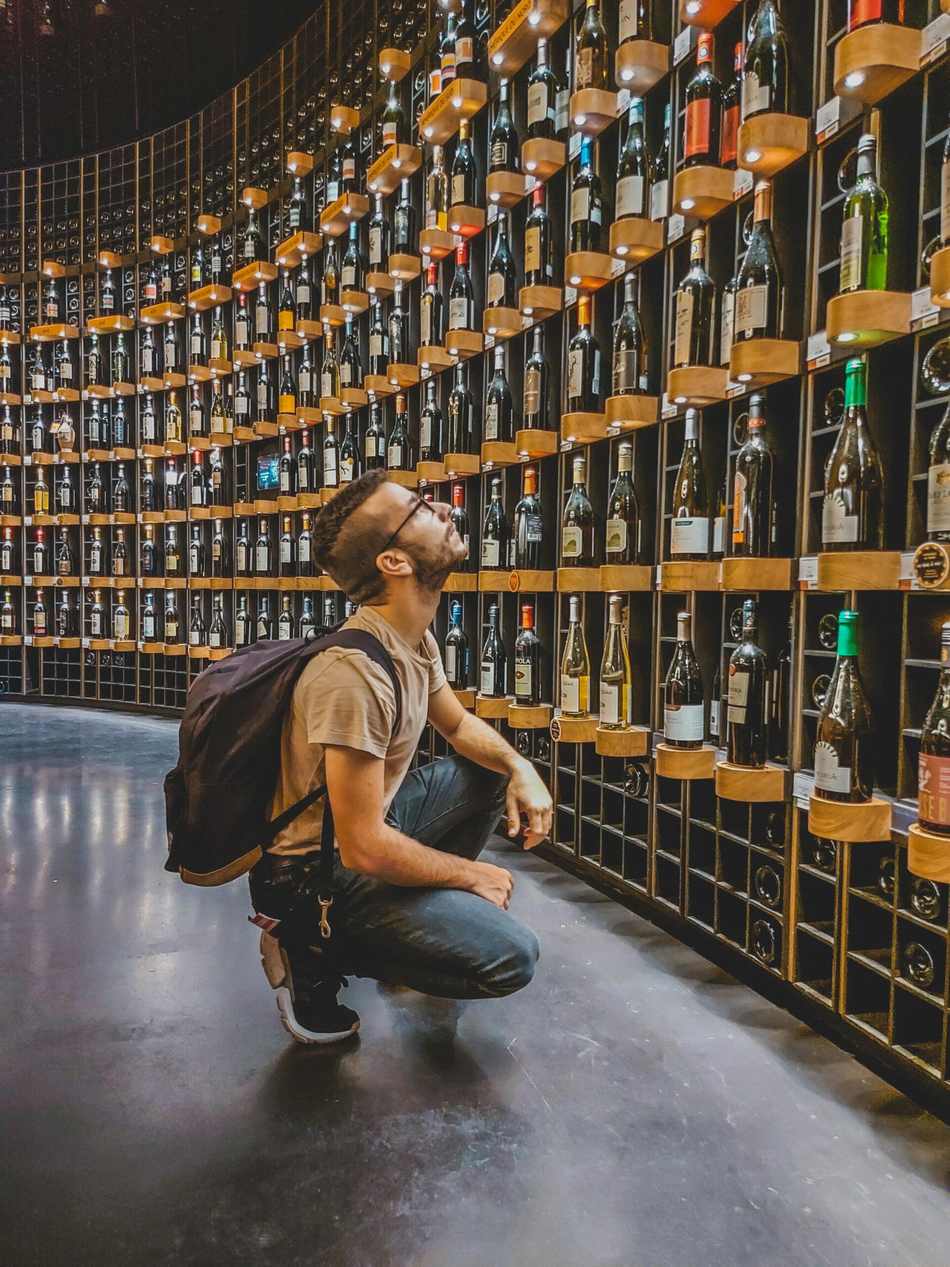 A person browsing wine bottles in a shop with a calm, curious mood
