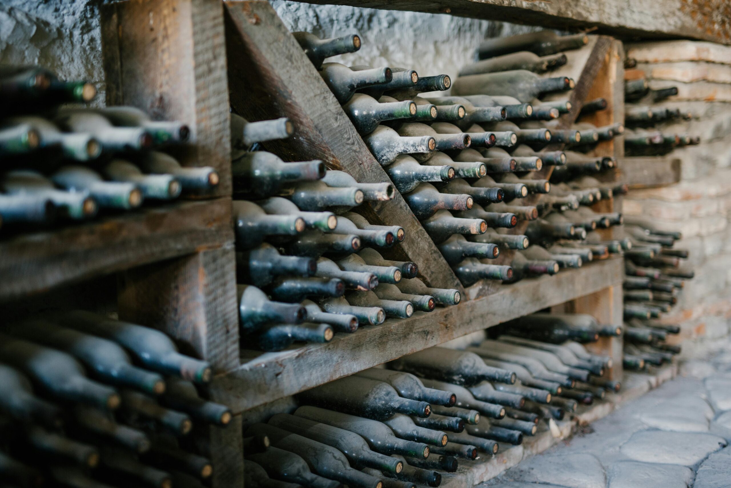 Dusty wine bottles resting in a cellar, representing aging myths and realities