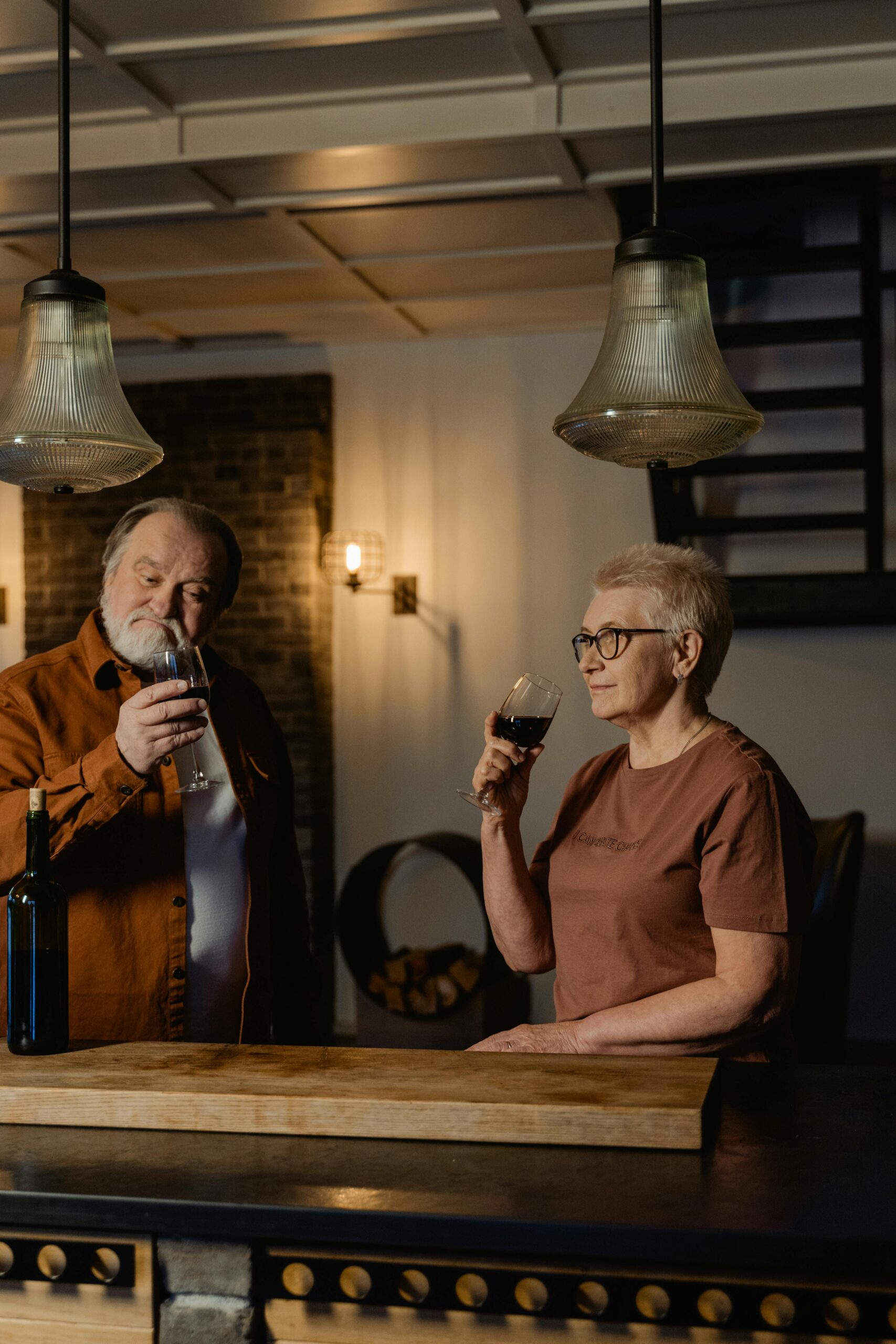 Two people enjoying a quiet wine moment at home with glasses on a table